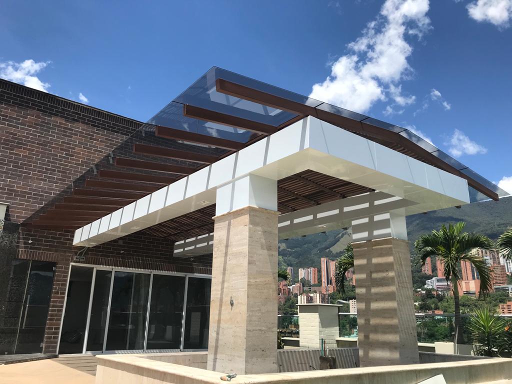 Pérgola en vidrio templado con difusores de luz en madera